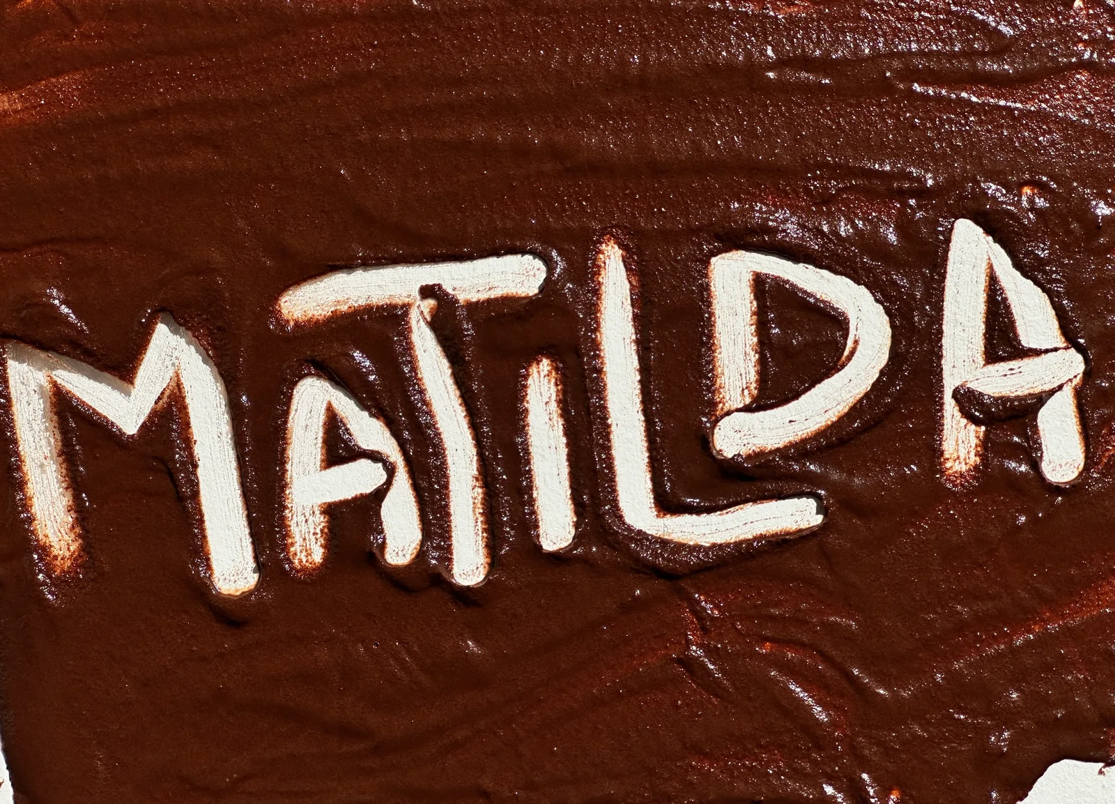 La palabra Matilda escrita a mano con crema clara sobre el ganache de chocolate